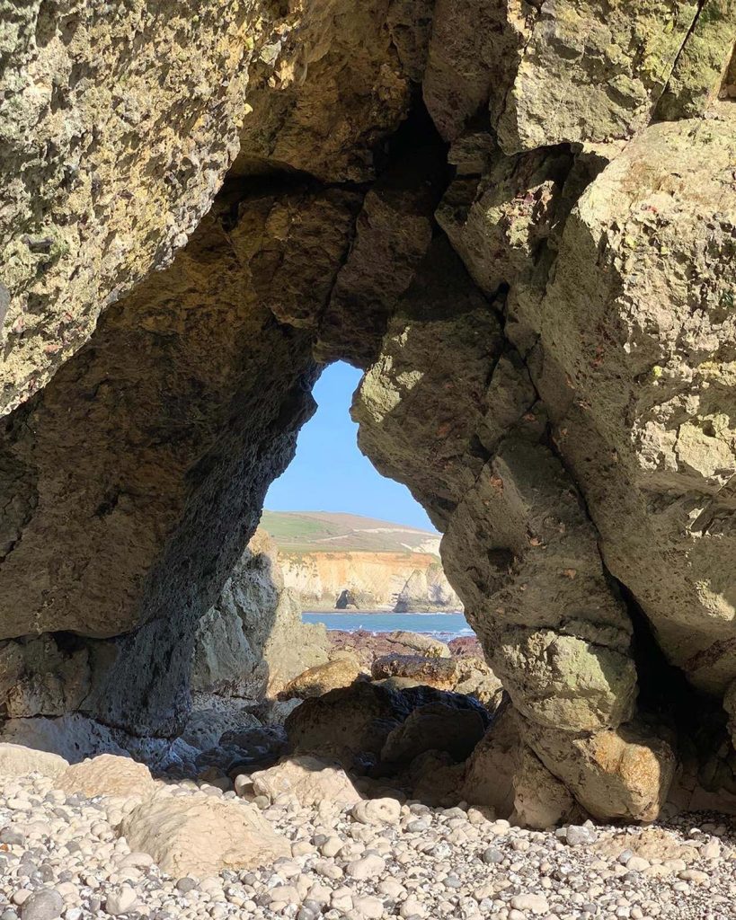 Looking through a triangular hole in the rocks with cliffs and landscape in the distance