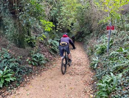 Mountain biker cycling up hill on gravel path