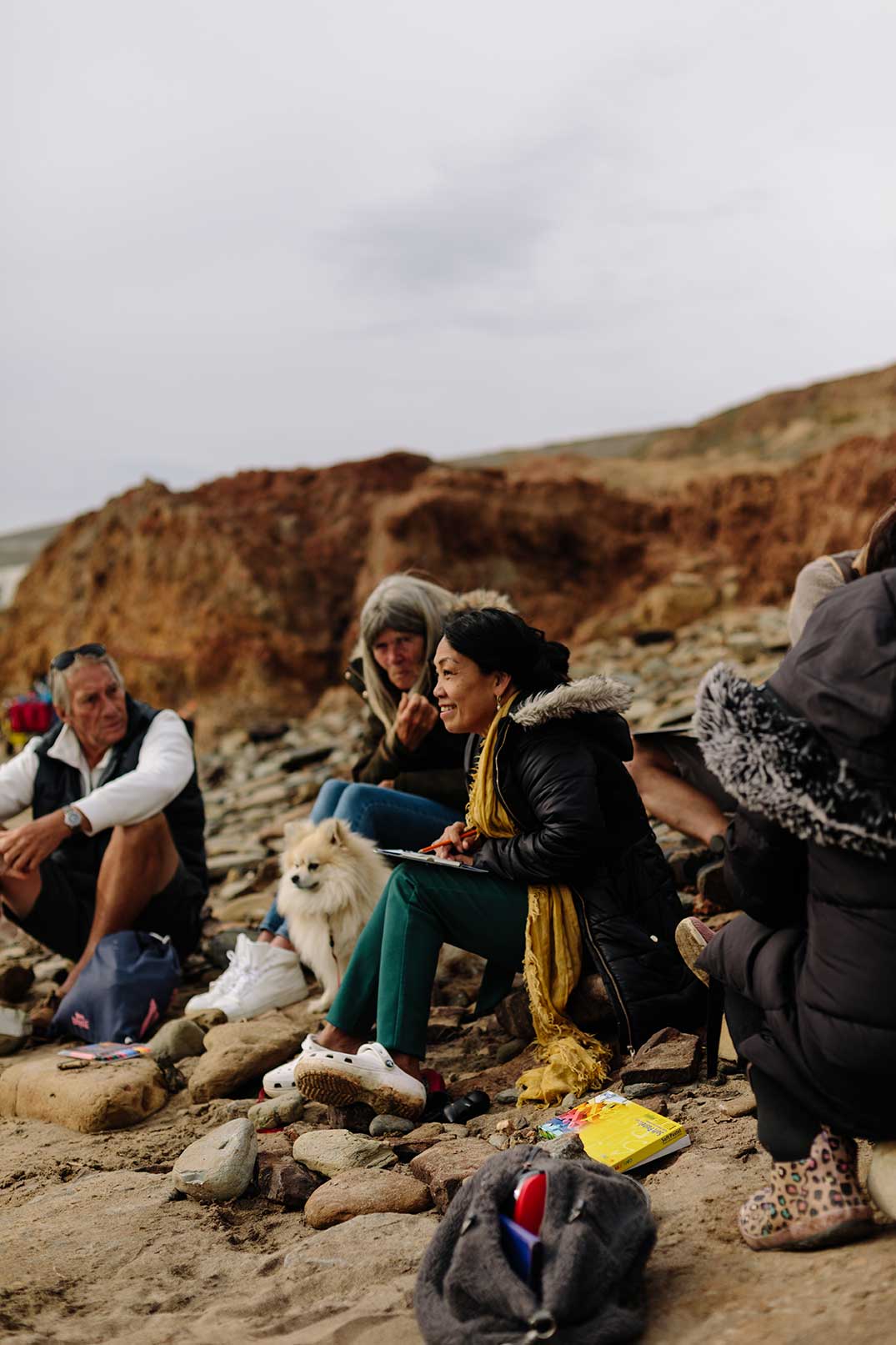 Small group sat on the beach talking at nature session wearing winter clothes 