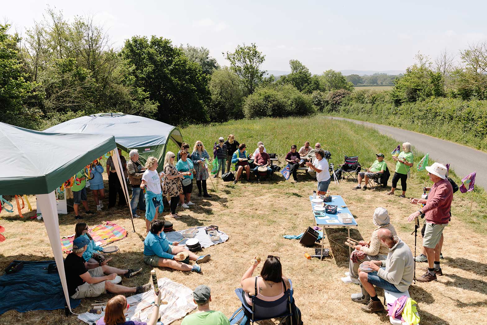 Overhead photo of carnival and drumming group in a field at a nature reserve on a sunny day