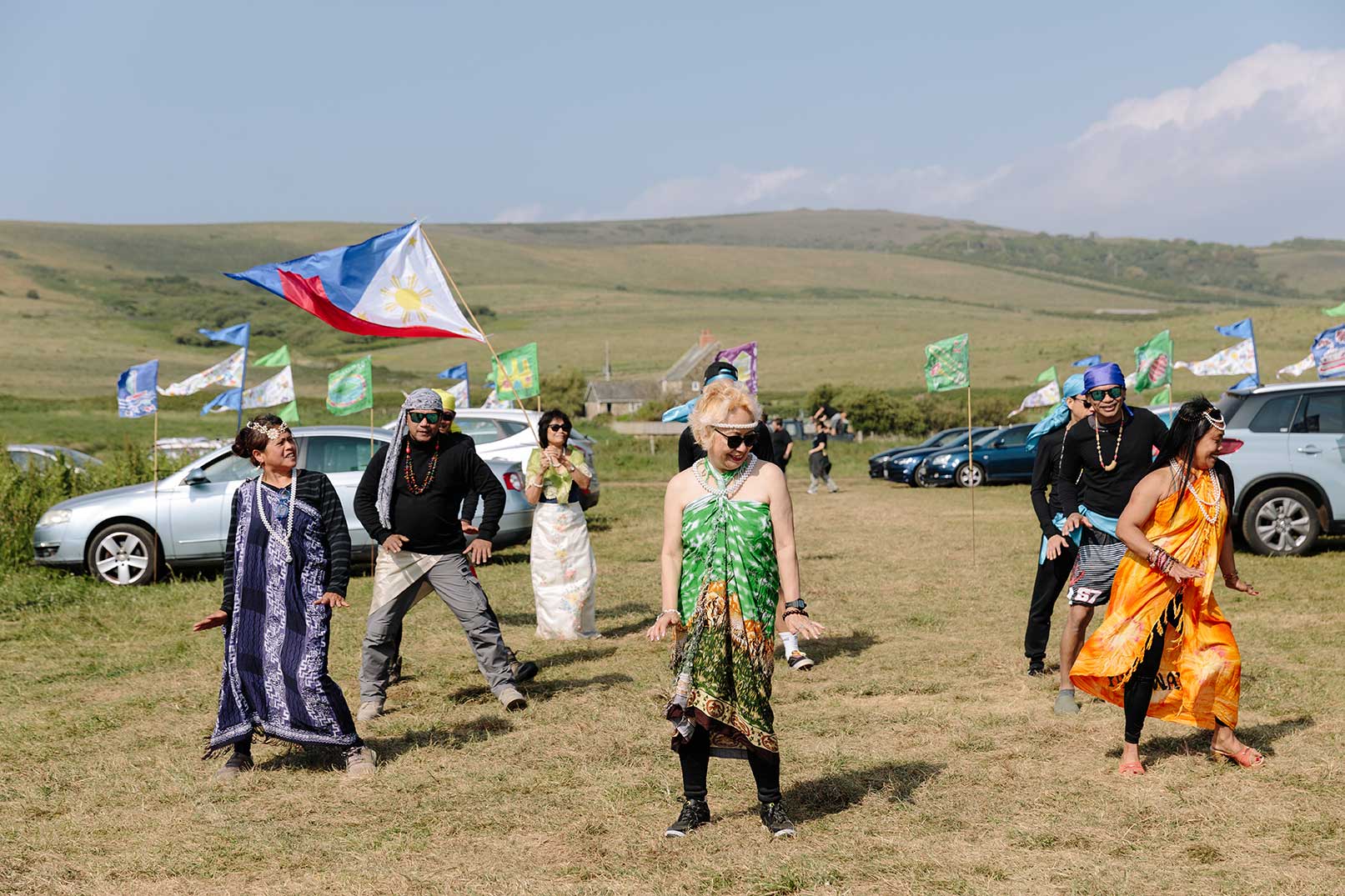 Traditional Pilipino dance with costume in costal field with decorated flags behind