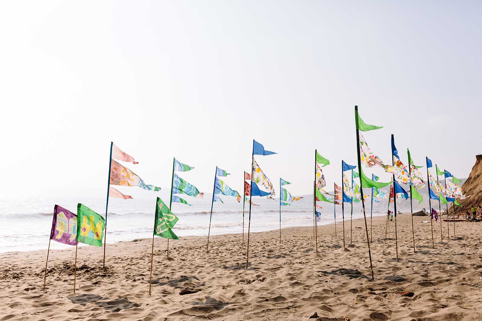 Flags blowing in the wind on sandy beach hand painted and drawn by community groups