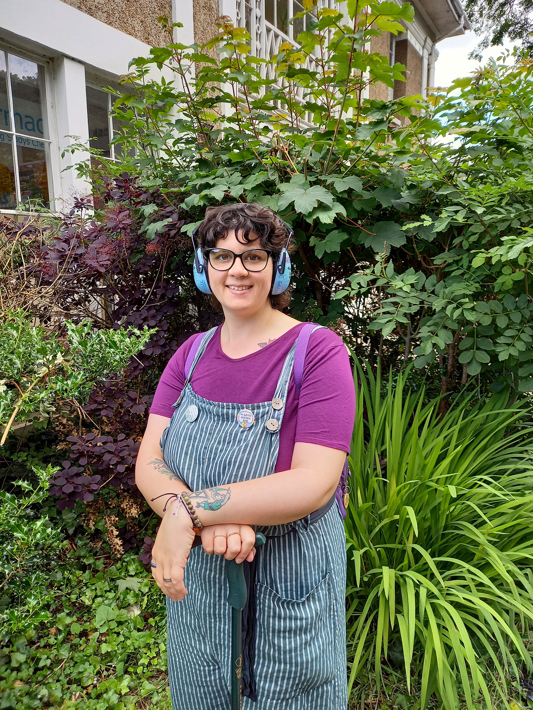 Photo of writer wearing ear defenders with green and purple plants in the background