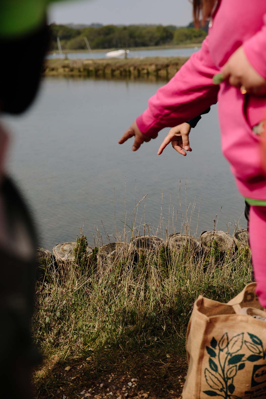 Close up photo of group members fingers pointing into the water at fish they have seen swimming