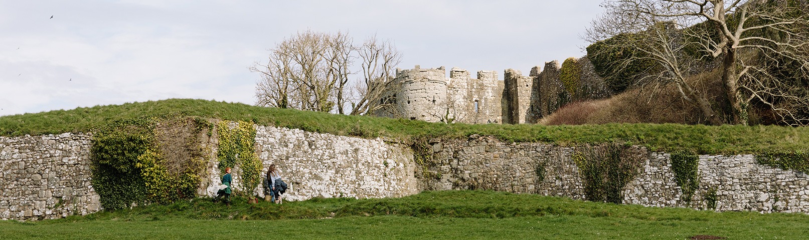 Carisbrooke Castle in winter sitting behind a stone wall covered with green moss and ivy