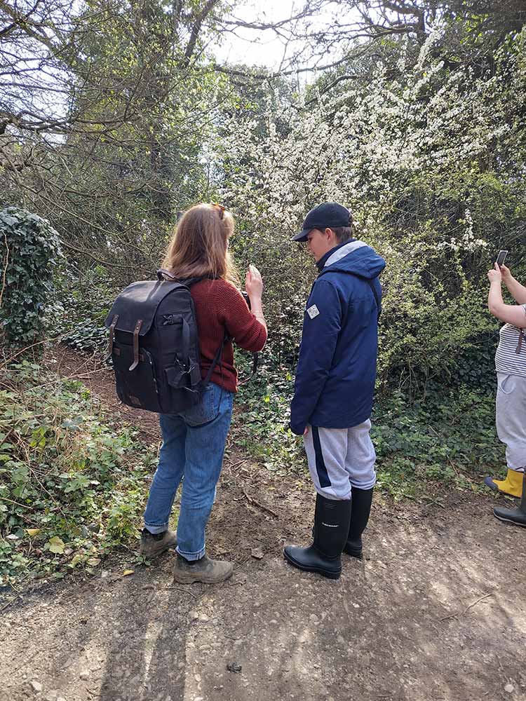 Photo of a photographer with a young person giving a workshop in the forest with blossom in the background