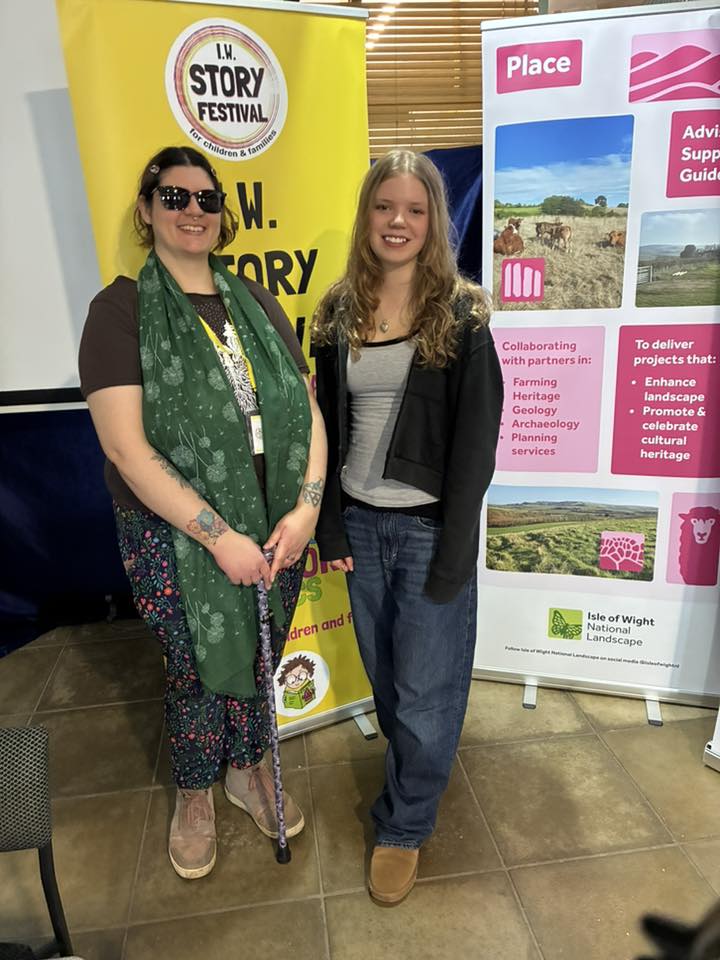 Young performer and writer stood in front of story festival and nature banners