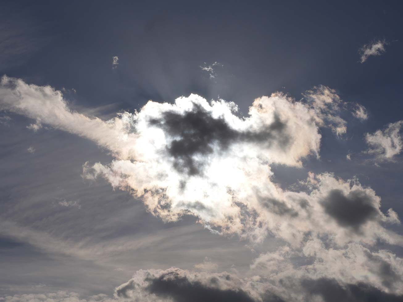 Sun behind the clouds against a dark blue sky